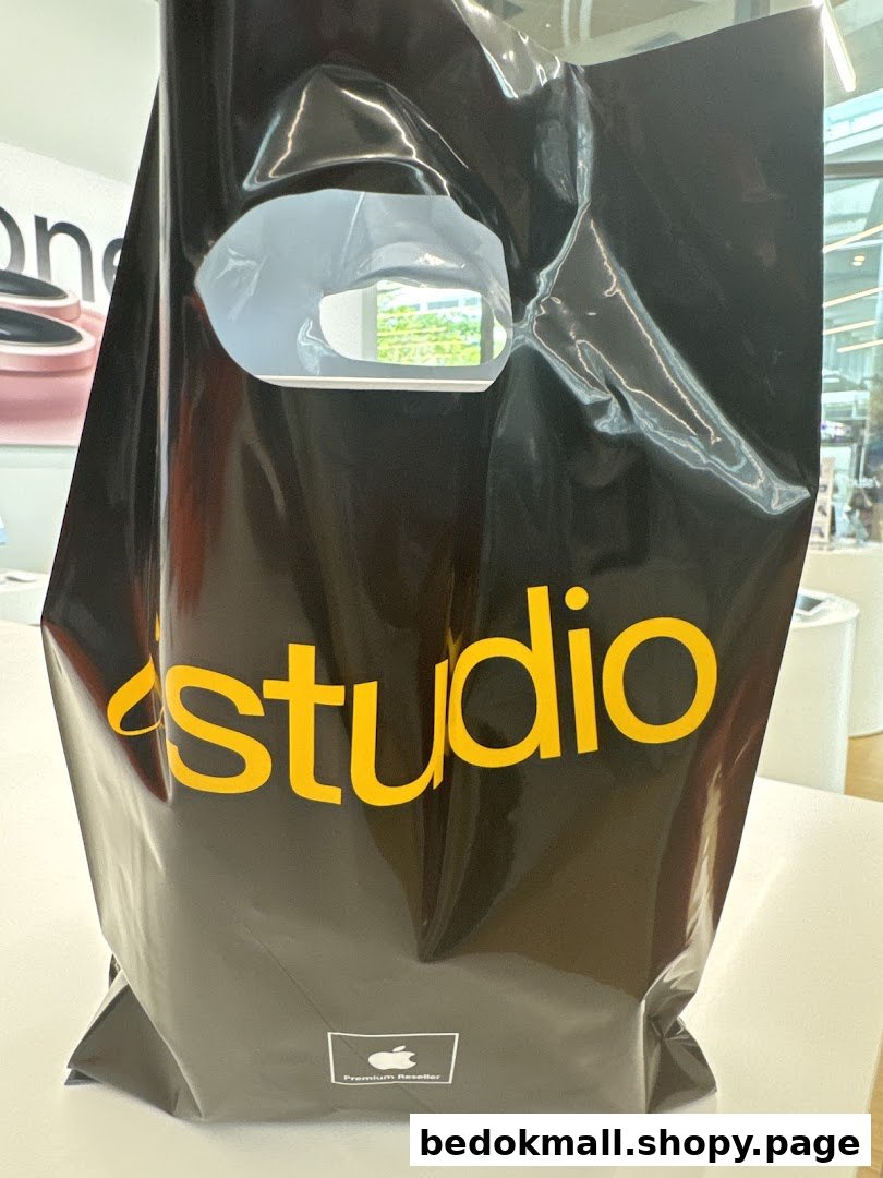 Black iStudio shopping bag with yellow logo on a white table.