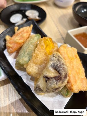 A plate of assorted fried vegetables or tempura on a black dish.