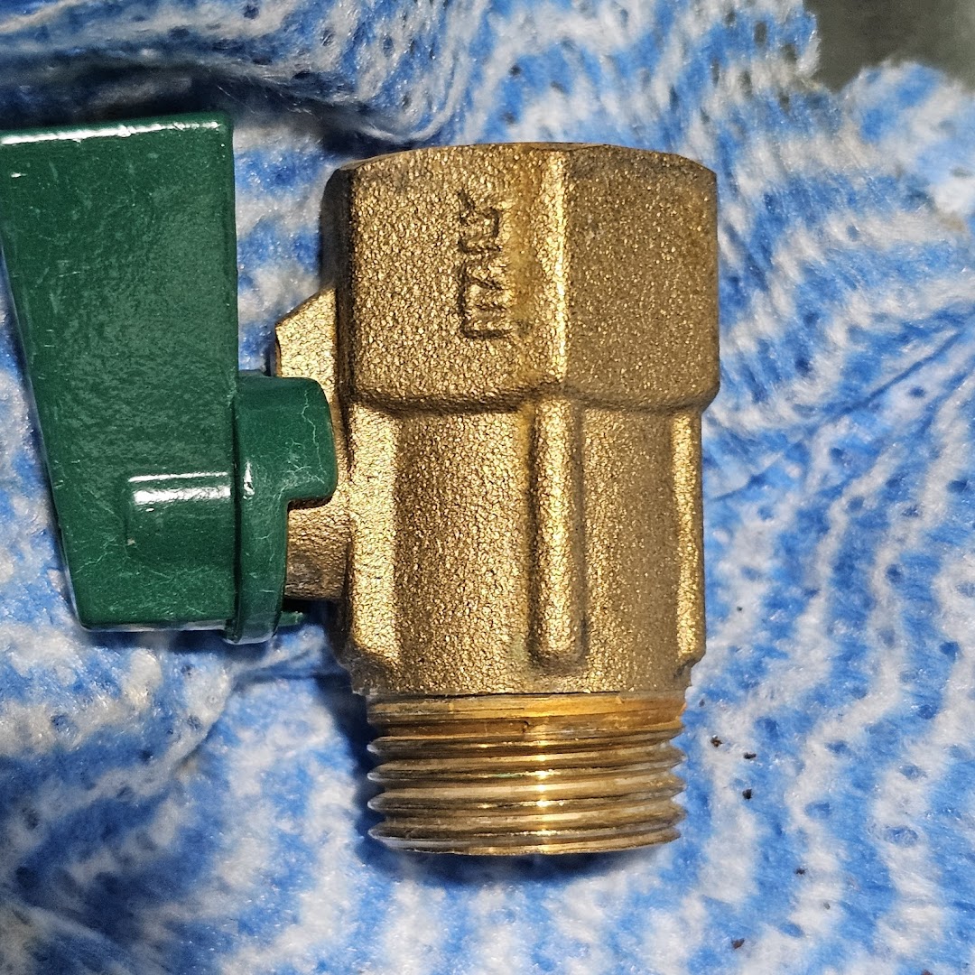 Close-up of a brass valve with a green handle and threaded end.