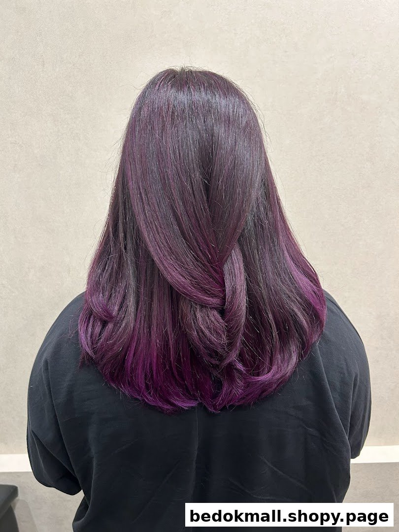 Back of person with long dark hair featuring purple highlights and a loose braid.