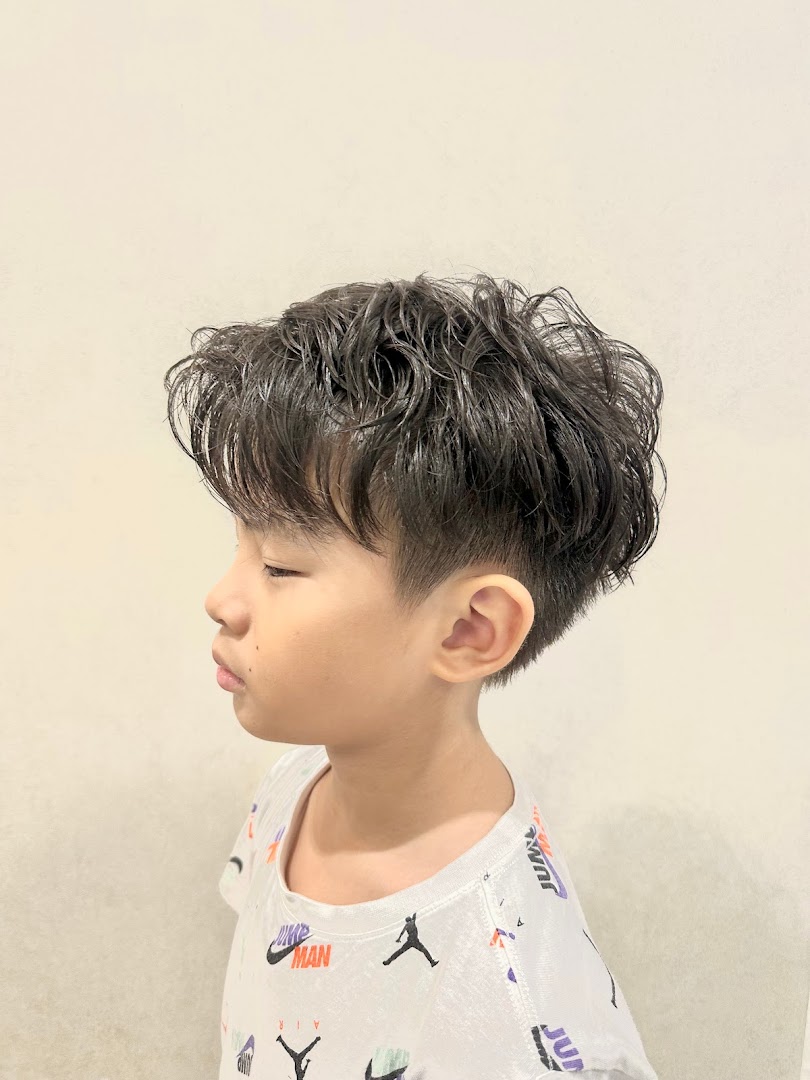 A child with a fresh haircut, viewed from the side.