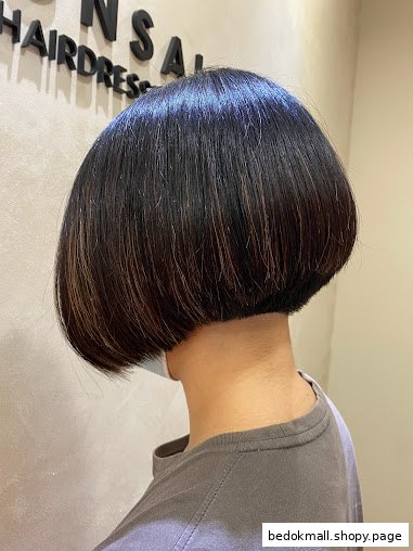 Back of a person's head with a short bob haircut inside a salon.