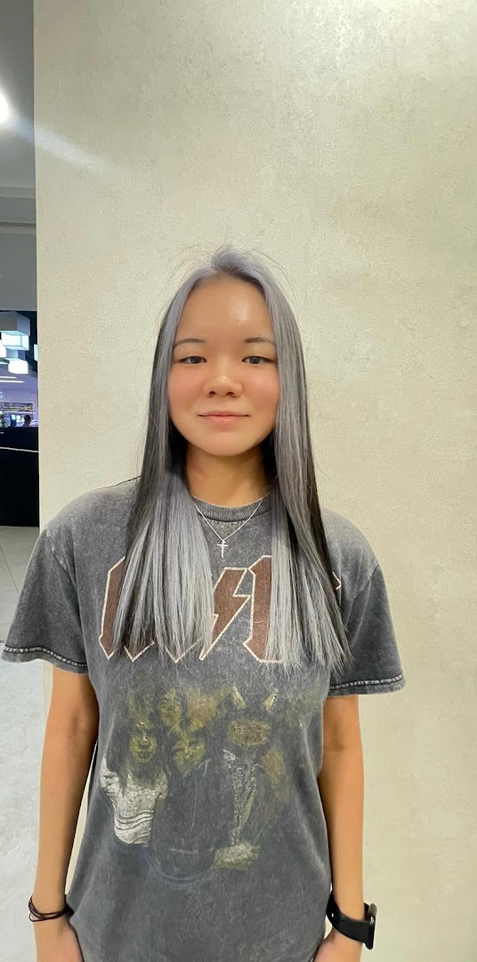 Young woman with long grey and black hair in a salon setting.