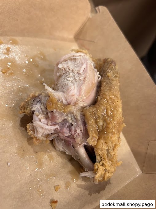 Partially eaten fried chicken in a cardboard box.