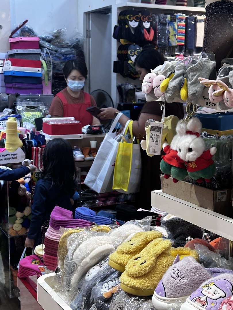 Interior view of a retail shop with products, staff, and customer at the counter.