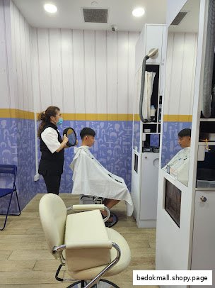 A stylist holds a mirror for a customer getting a haircut inside a salon.