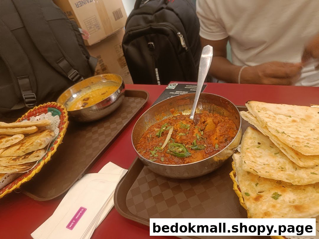 Food on trays at a table with a person and backpacks in the background.