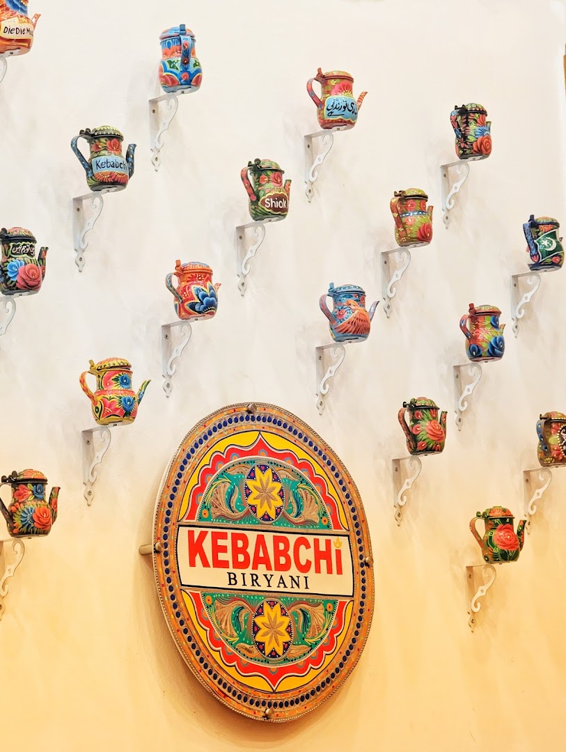 Interior wall with colorful teapots and a Kebabchi Biryani shop sign.