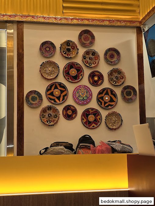 Interior wall decorated with colorful plates above a yellow counter with bags.