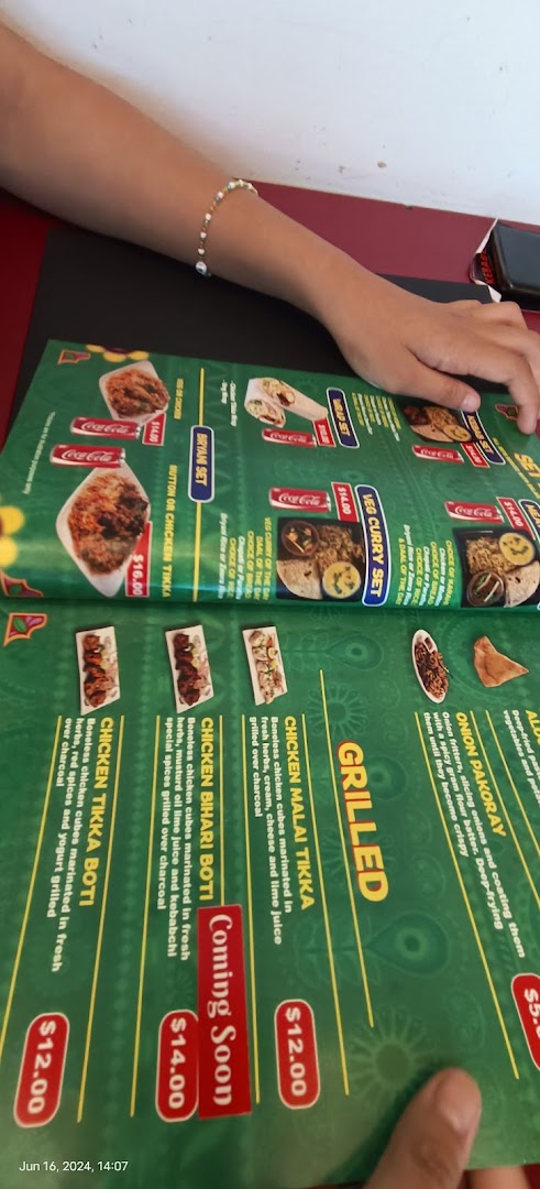 A person's hands holding a green menu displaying various food items and prices.