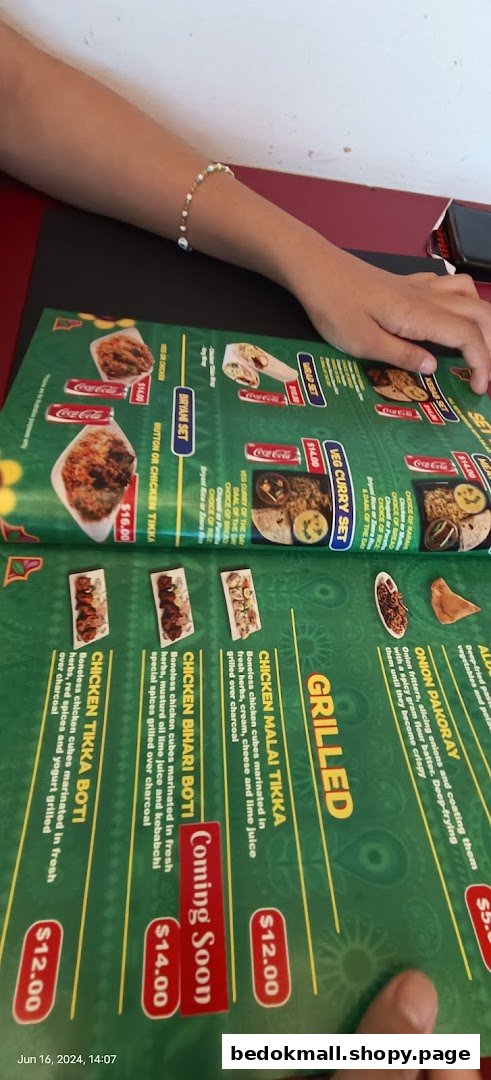 A person's hands holding a green menu displaying various food items and prices.