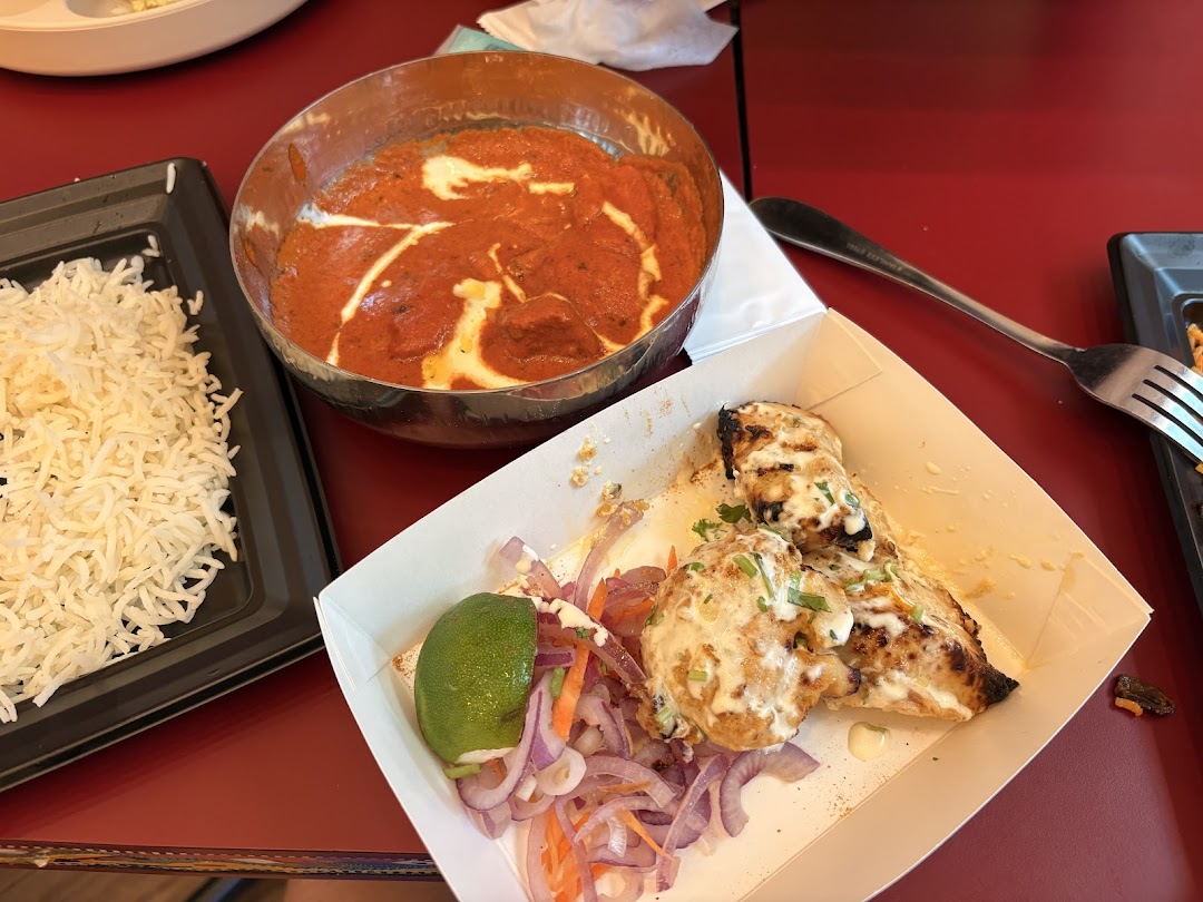 Table setting with Indian food: rice, curry, and grilled chicken.