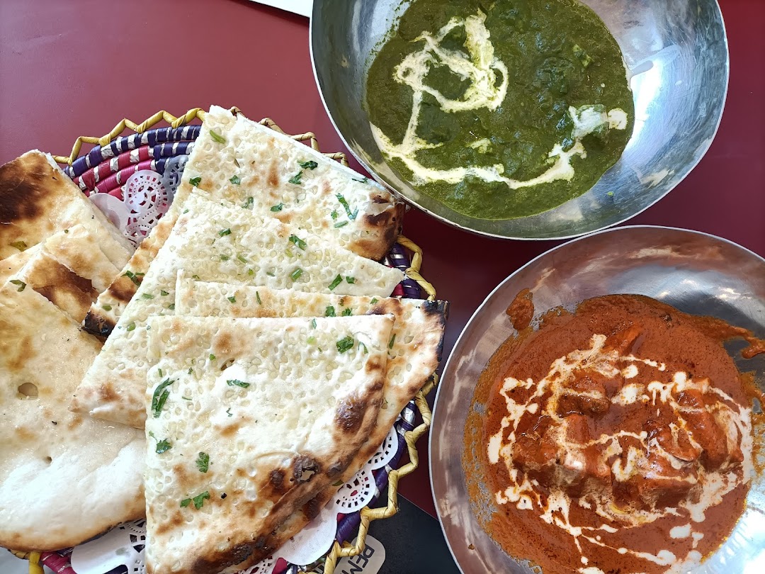Naan bread and two bowls of curry on a red table.