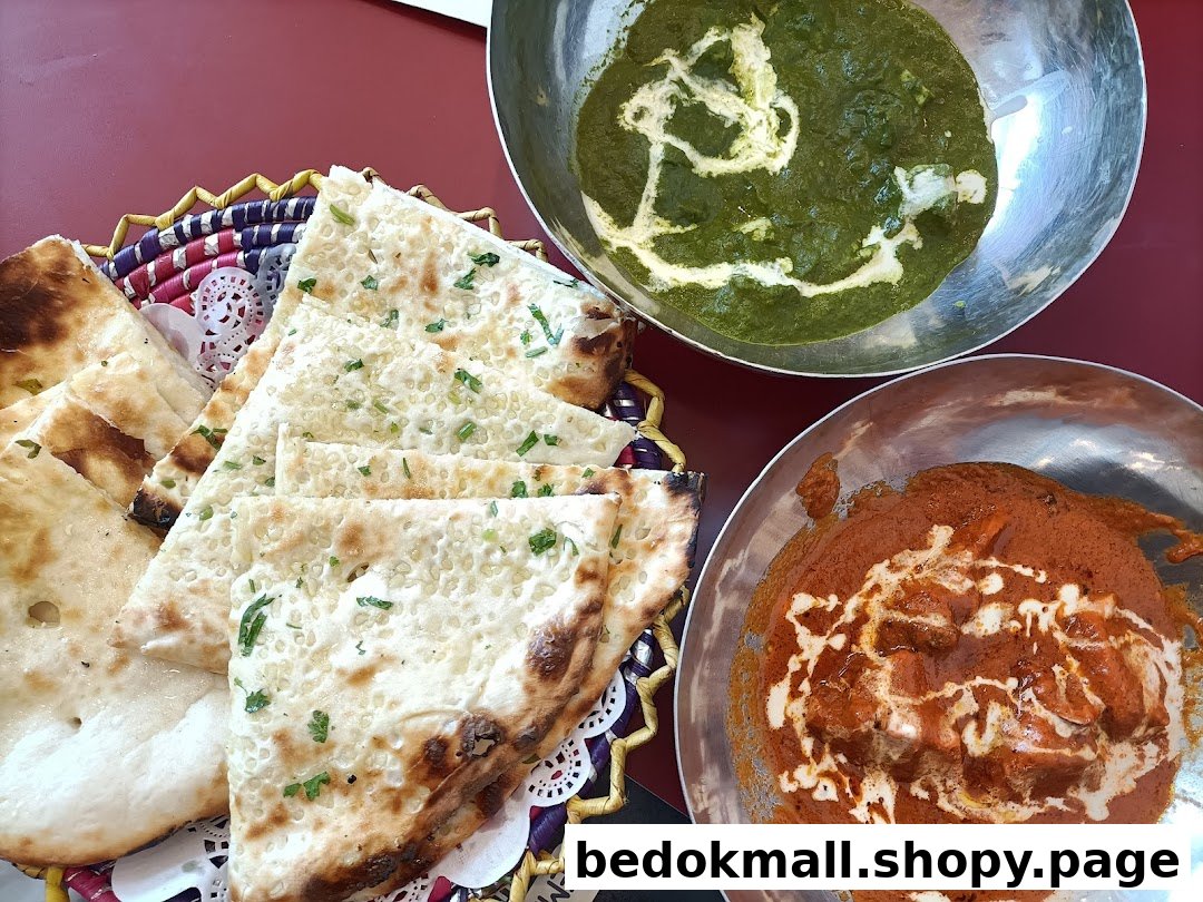 Naan bread and two bowls of curry on a red table.