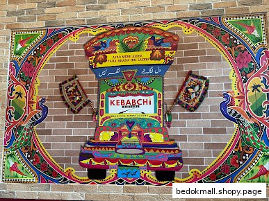 Colorful mural of a decorated truck and peacocks on a brick wall.