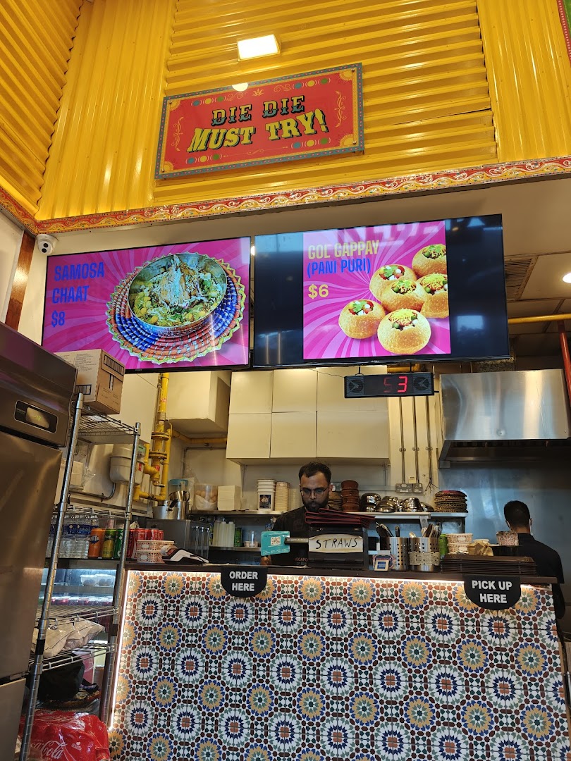 Food counter with digital menus displaying items and prices, and staff.