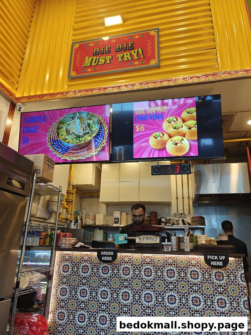 Food counter with digital menus displaying items and prices, and staff.