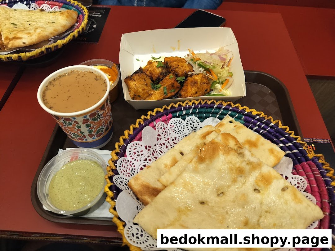 A tray with naan, chicken, tea, and sauces on a red table.