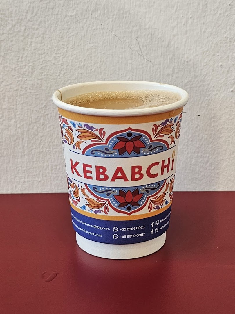 A branded paper cup filled with a beverage on a red surface.