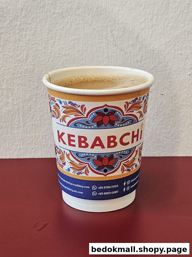 A branded paper cup filled with a beverage on a red surface.