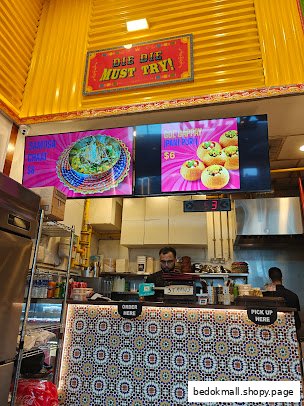Shop interior with counter, staff, and digital menu screens displaying food.
