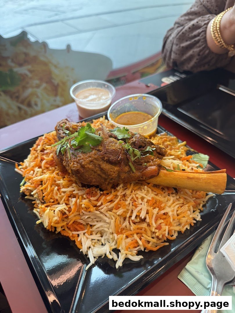 A plate of biryani with a lamb shank and sauces on a table.