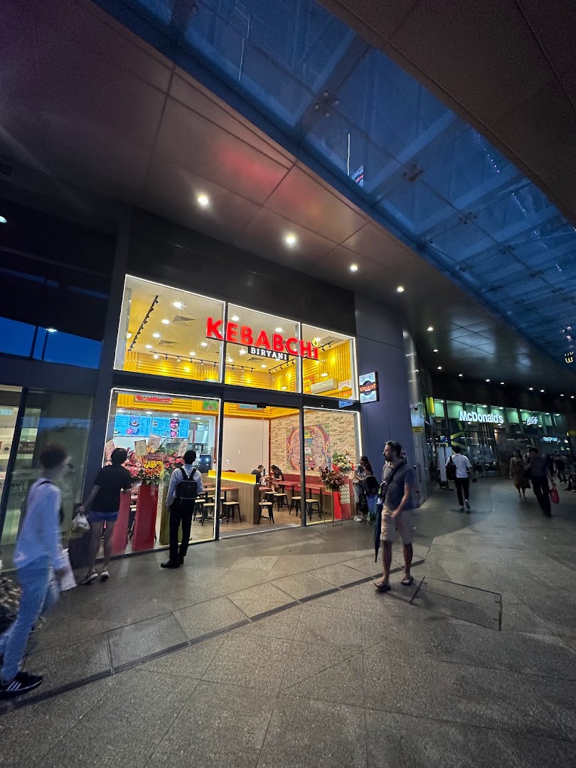 Exterior view of Kebabchi Biryani shop at night with people walking by.