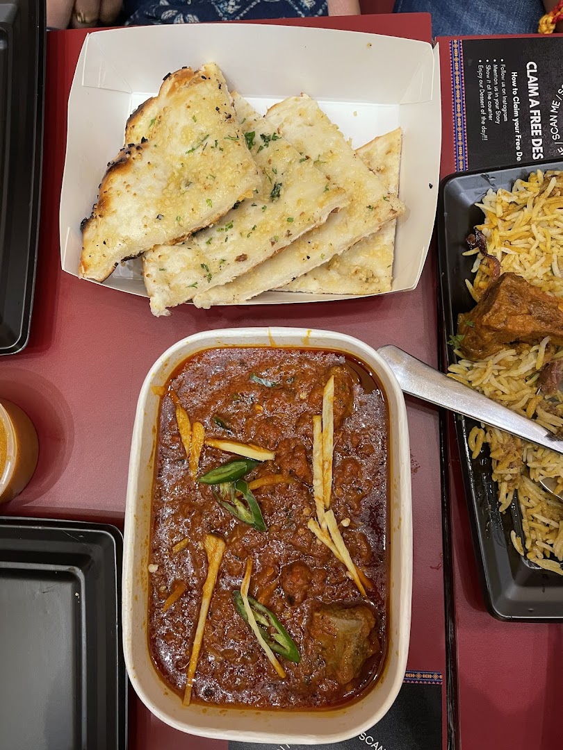 Table with naan bread, a curry dish, and biryani.
