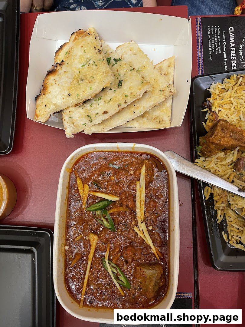 Table with naan bread, a curry dish, and biryani.