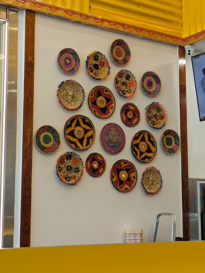 Interior wall decorated with colorful woven plates above a yellow counter.