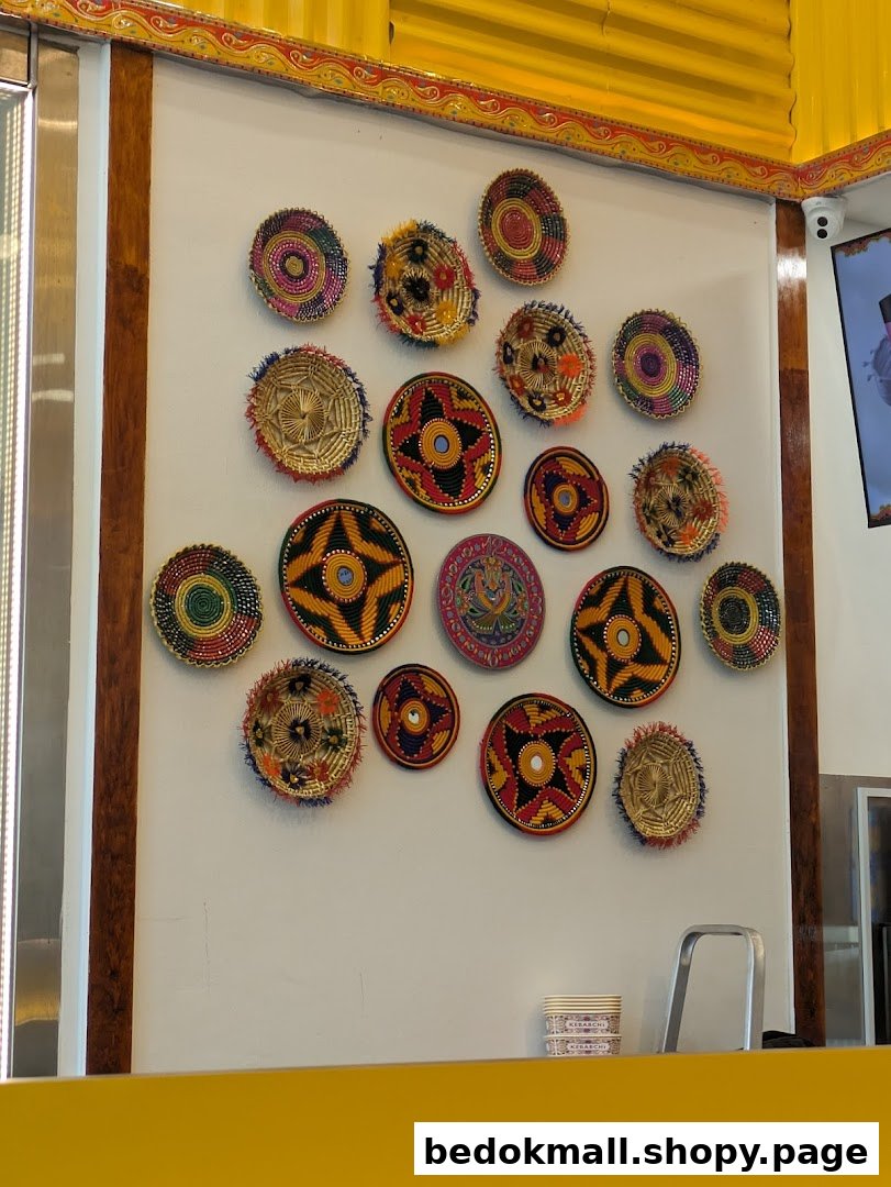 Interior wall decorated with colorful woven plates above a yellow counter.