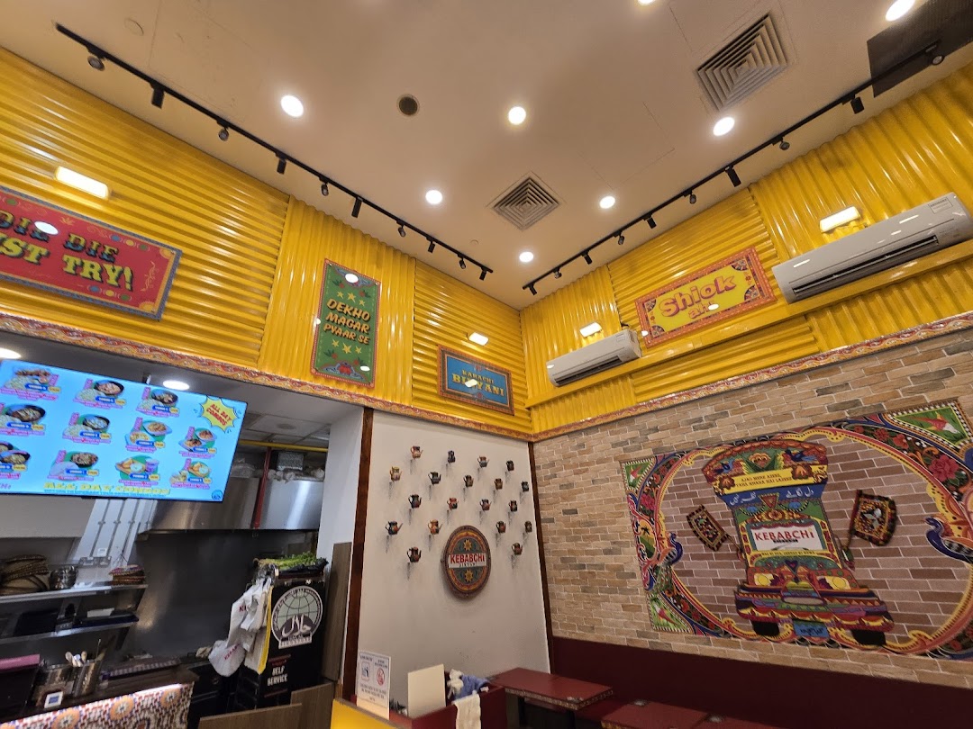 Colorful restaurant interior with a menu screen, kitchen counter, and decorated walls.