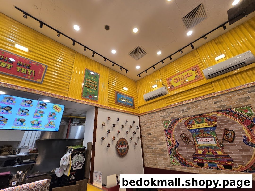 Colorful restaurant interior with a menu screen, kitchen counter, and decorated walls.
