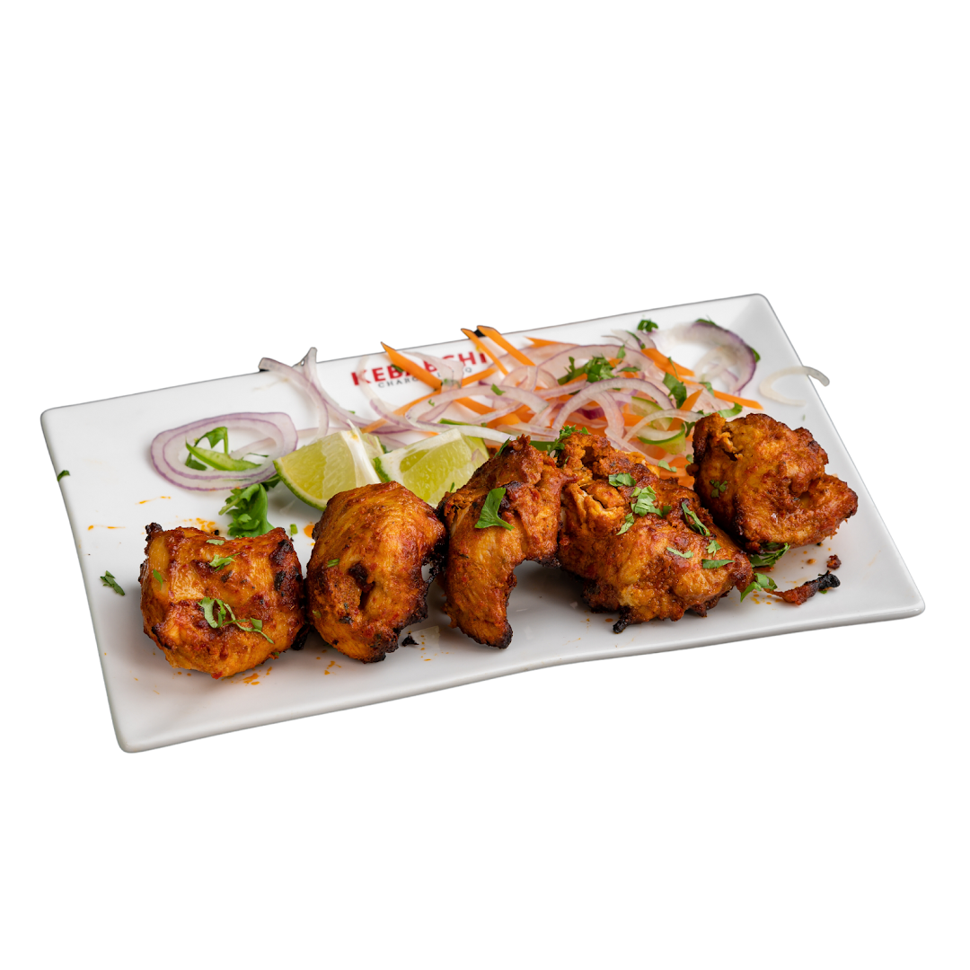 Plate of cooked chicken pieces with salad and lime wedges.
