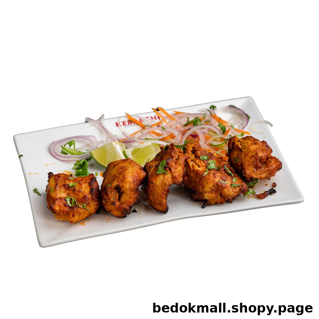 Plate of cooked chicken pieces with salad and lime wedges.