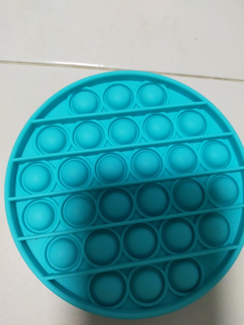 Close-up of a teal circular pop-it fidget toy.