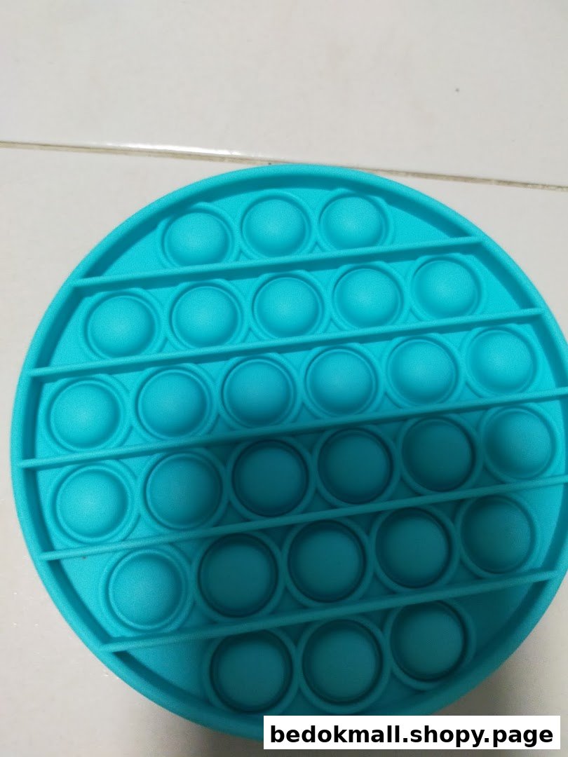Close-up of a teal circular pop-it fidget toy.