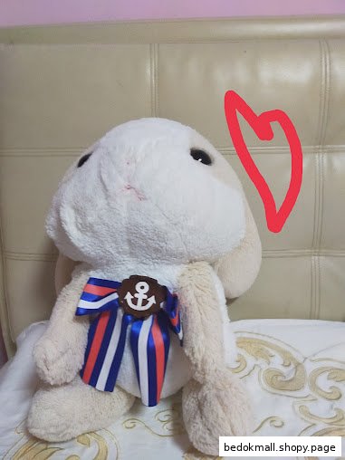 A plush bunny toy with a blue, red, and white ribbon and an anchor charm.