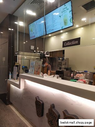 Interior view of a bubble tea shop counter with staff and digital menus.