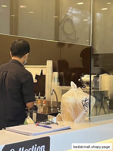 Staff member preparing drinks behind a counter in a bubble tea shop.