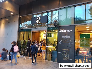 Exterior view of Koi Thé shop with customers queuing outside.