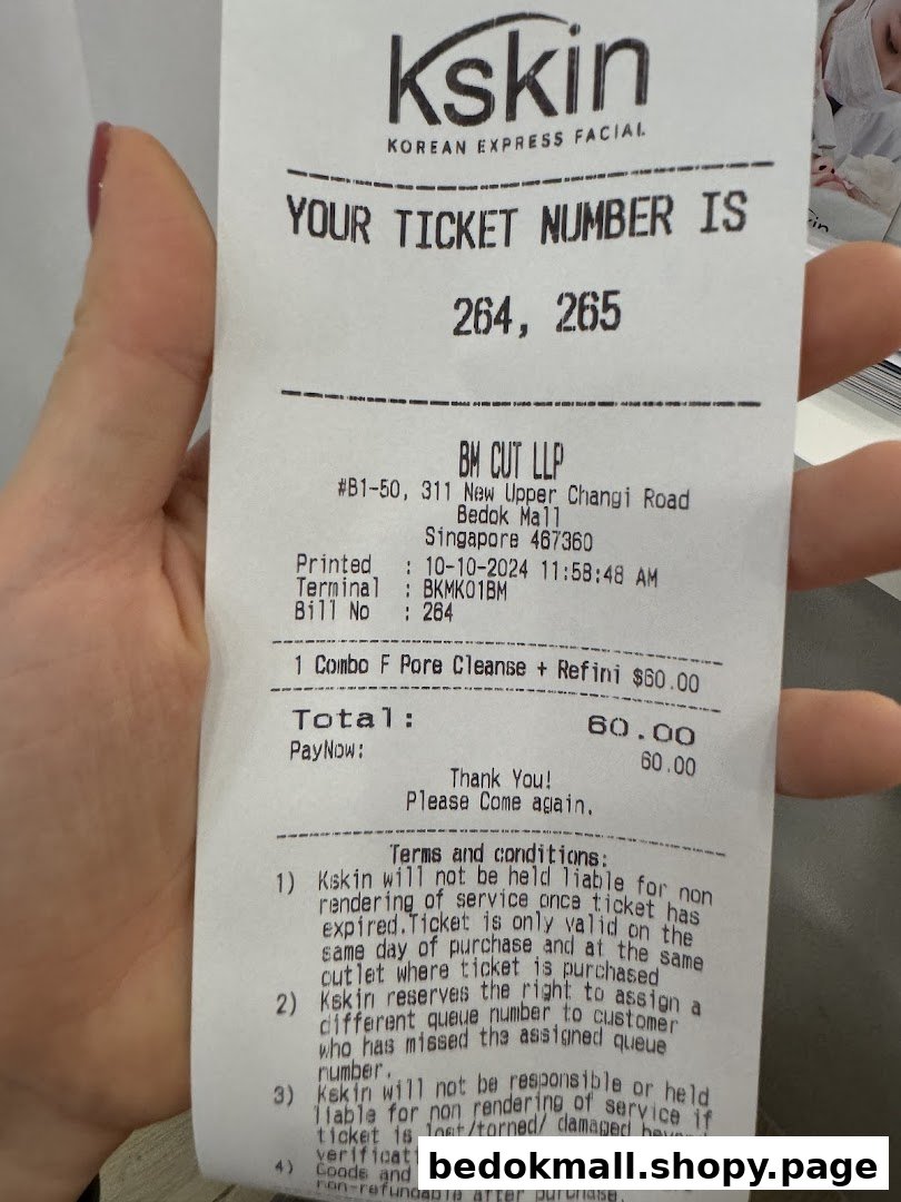 A hand holds a printed receipt for a Kskin Korean Express Facial service.