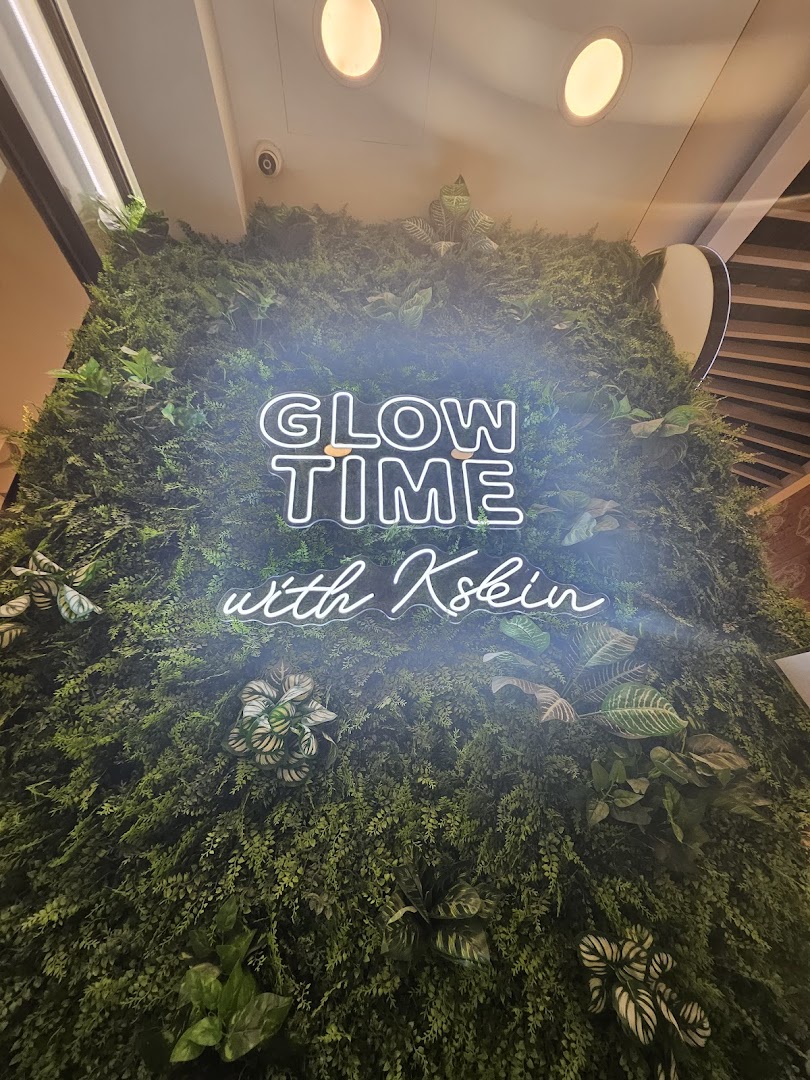 Green wall with a glowing neon sign 'GLOW TIME with Kskin'.