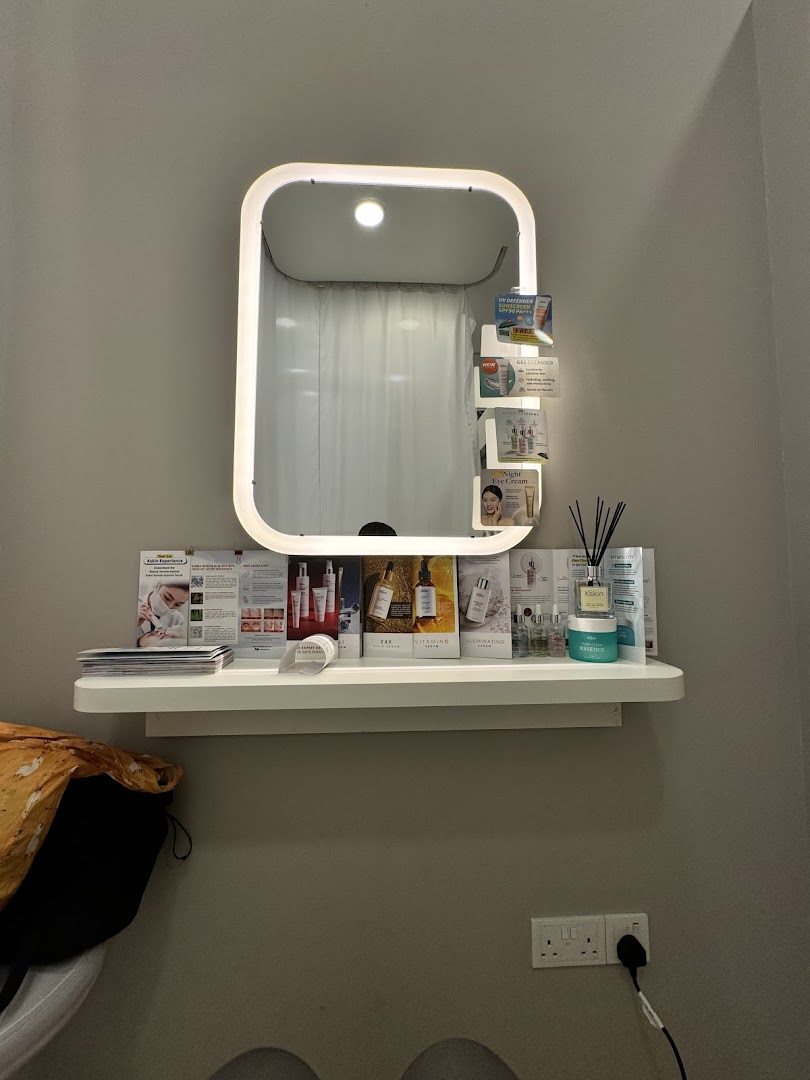 Lighted mirror above a shelf with product brochures and a diffuser.