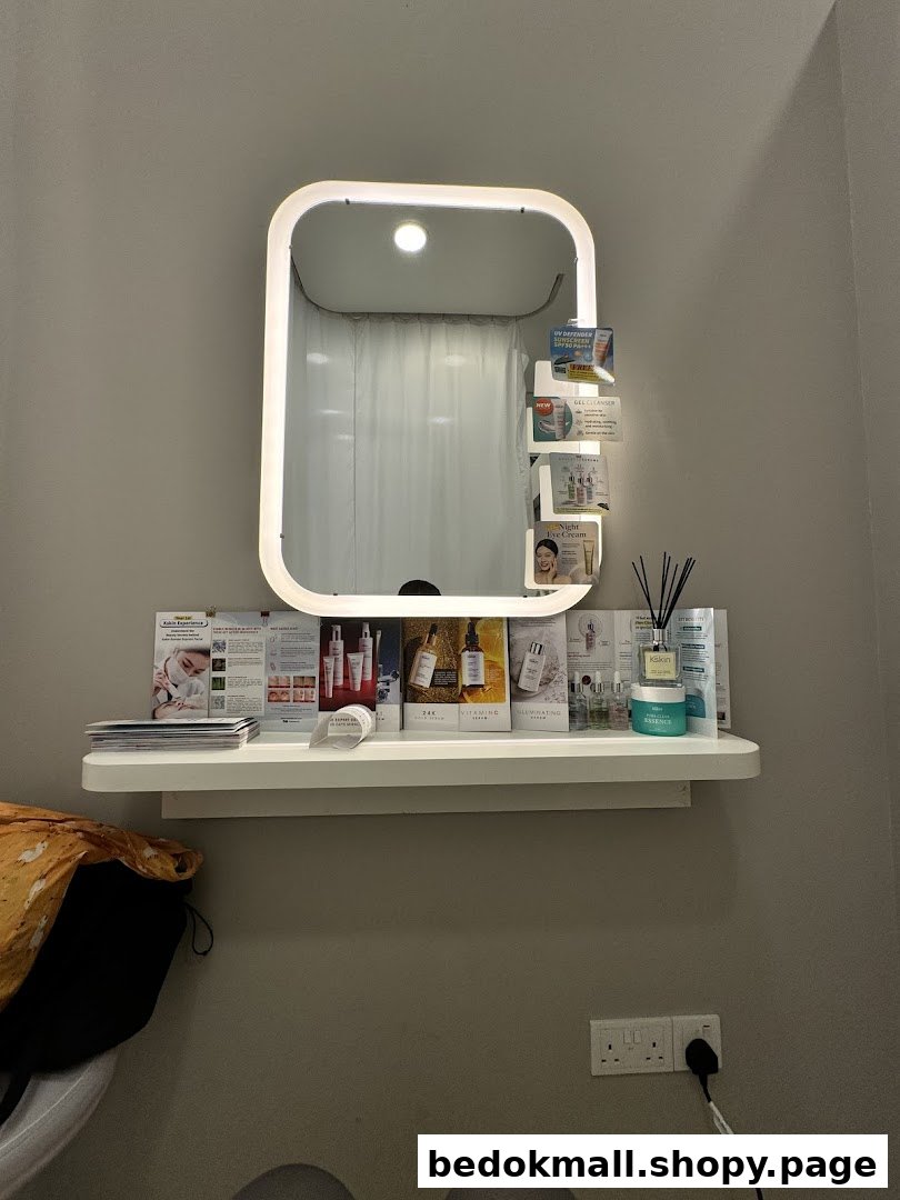 Lighted mirror above a shelf with product brochures and a diffuser.
