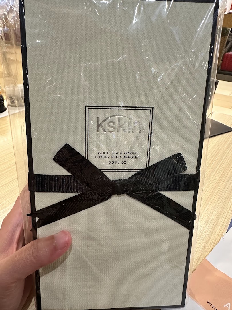 A hand holds a packaged Kskin luxury reed diffuser with a black ribbon.