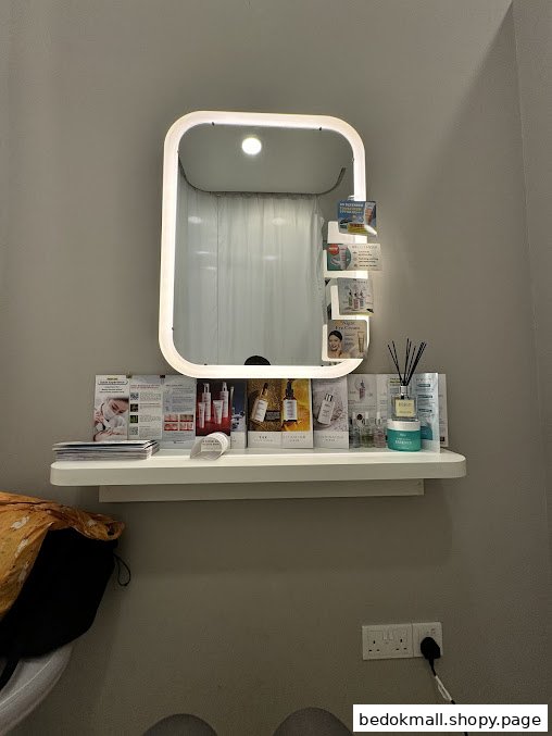 Interior view of a treatment room with an illuminated mirror and product display.