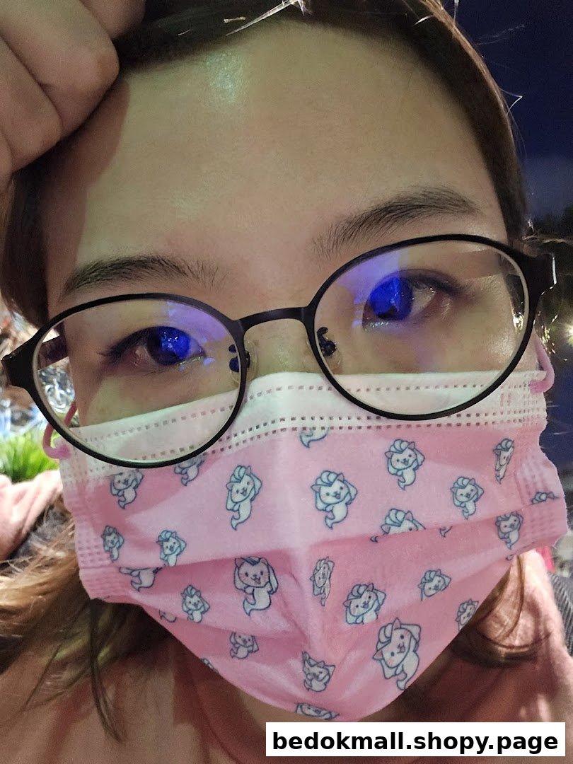 Close-up of a person wearing glasses and a pink patterned face mask.