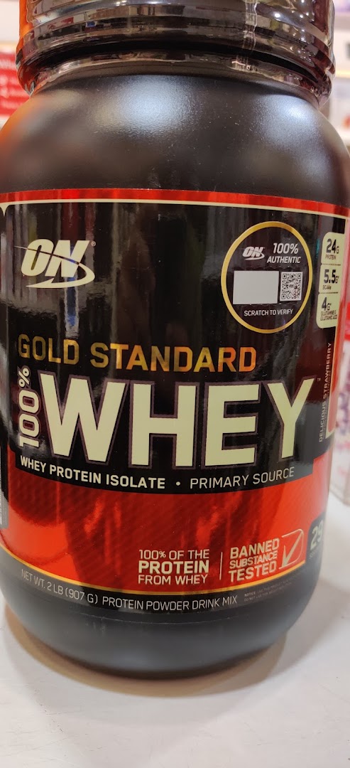 Close-up of a black and red tub of Gold Standard Whey protein powder.