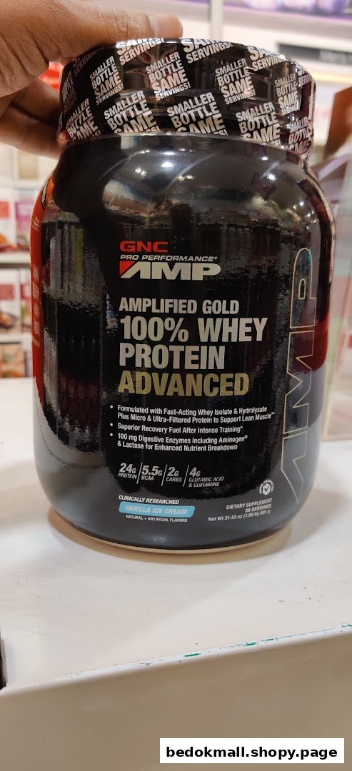 Hand holding a large black container of GNC whey protein.